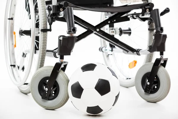 Інвалідне крісло для некоректної або інвалідної людини та футбольного м'яча — стокове фото