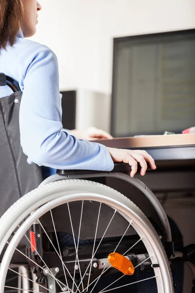Некоректна або інвалідна жінка, що сидить на робочому столі на інвалідному візку — стокове фото