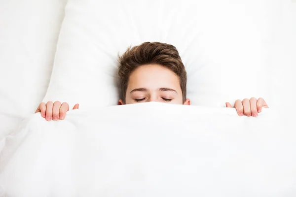 Sleeping child boy lying bed hiding face with blanket — Stock Photo, Image