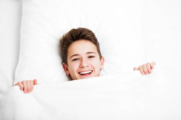 Счастливый красивый зубастый улыбающийся мальчик лежит кровать и отдыхает — стоковое фото