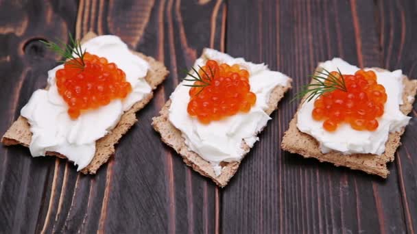 Galletas saladas con queso crema y caviar rojo de cerca — Vídeos de Stock