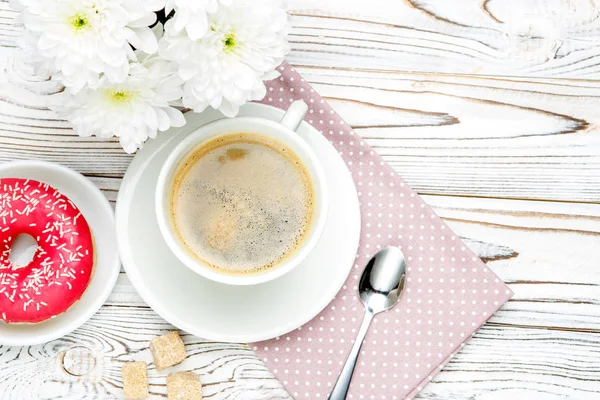 Donut und Kaffee, Blumen auf Holzgrund — Stockfoto