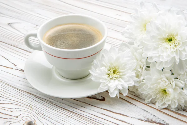 Kopp kaffe och blommor på ljus träbord — Stockfoto
