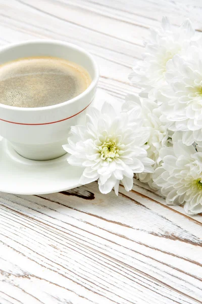 Kopp kaffe och blommor på ljus träbord — Stockfoto