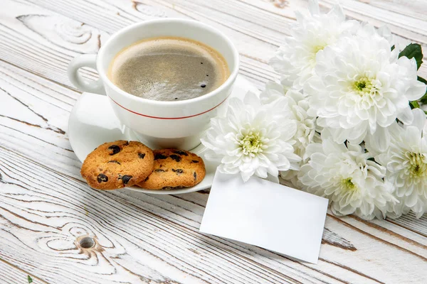 Cup of coffee and flowers on light wooden table — Stock Photo, Image