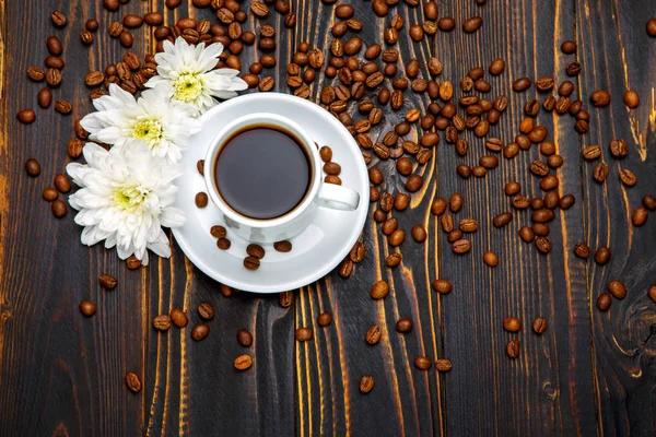 Filiżankę kawy i kwiaty na ciemny drewniany stół — Zdjęcie stockowe
