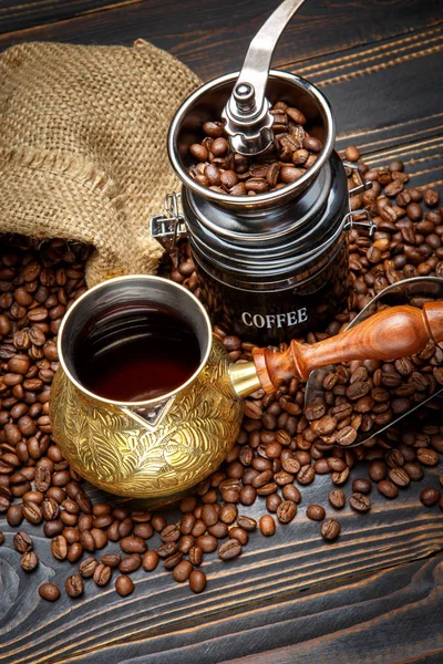 Kaffeemühle und geröstete Bohnen auf Holzgrund — Stockfoto