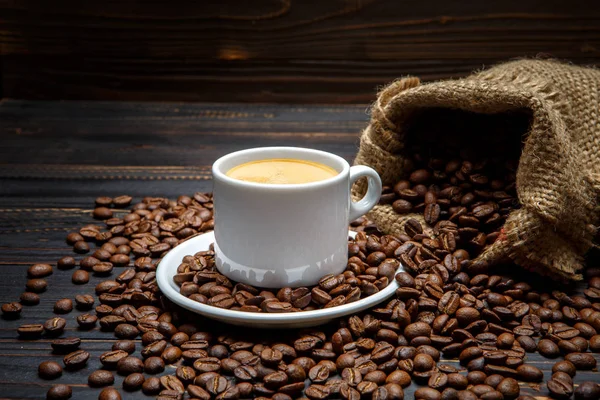 Cup of coffee and beans on wooden background — Stock Photo, Image