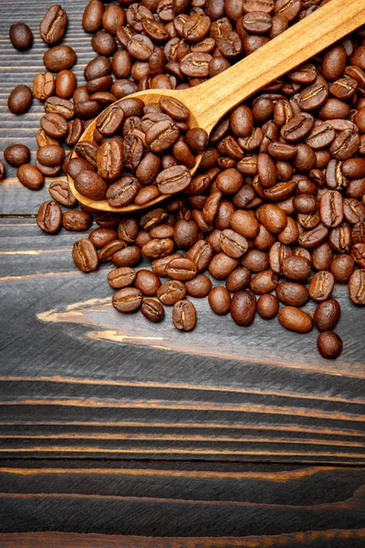 Dřevěná lžíce pražených kávových zrn na stole — Stock fotografie