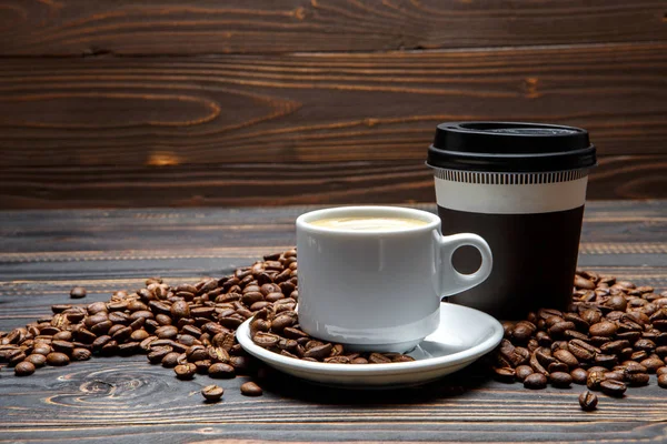 Gebrande koffiebonen en cup op houten achtergrond — Stockfoto