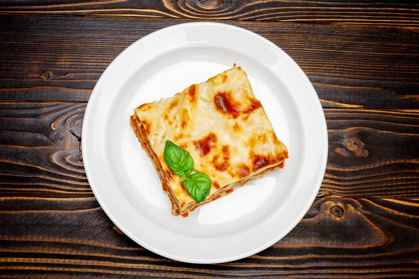 Gedeelte van smakelijke lasagne op houten achtergrondkleur — Stockfoto