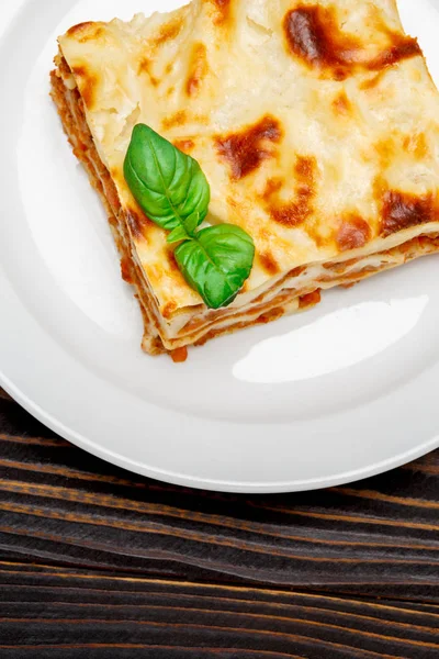 Část chutné lasagne na dřevěné pozadí — Stock fotografie