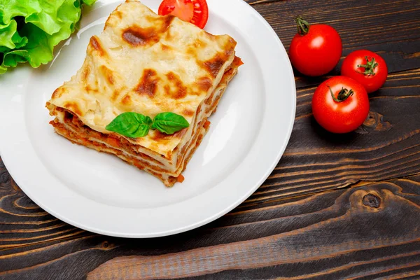 Portion of tasty lasagna on wooden backgound — Stock Photo, Image