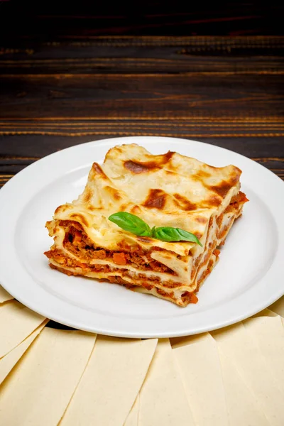 Része ízletes lasagna a fából készült háttér — Stock Fotó