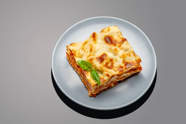 Gedeelte van smakelijke lasagne op grijze achtergrond — Stockfoto