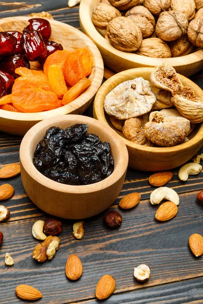 Ovoce sušené fíky, meruňky, švestky a ořechy na dřevěné pozadí — Stock fotografie