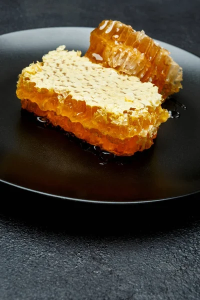 Favo de mel com mel no prato. fundo de concreto escuro — Fotografia de Stock
