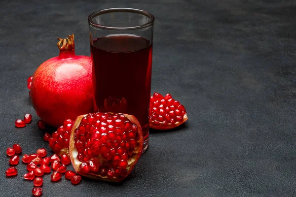 Pomegranate juice and seeds close-up on dark concrete background — Stock Photo, Image