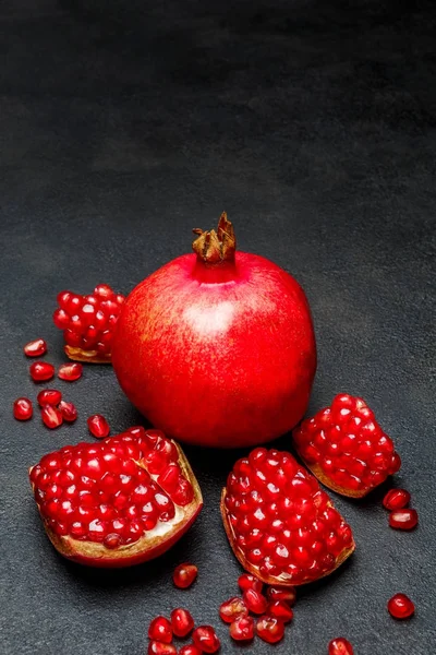 Pomegranate and seeds close-up on dark concrete background — Stock Photo, Image