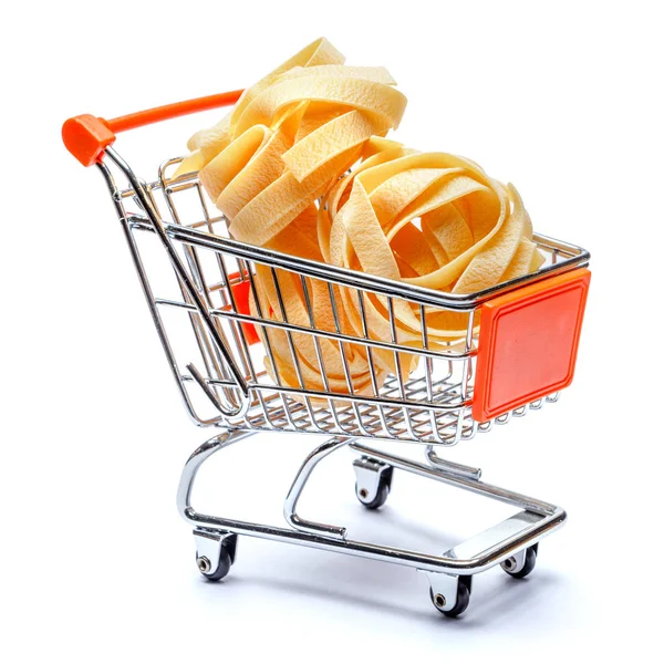 Raw fettuccine ribbon pasta in shopping cart on white background — Stock Photo, Image