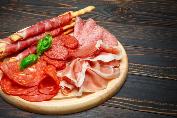 Piatto di carne affumicata fredda con braciole di maiale, prosciutto, salumi e bastoncini di pane — Foto Stock