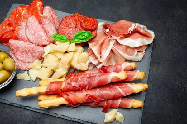 Piatto di carne affumicata fredda con braciole di maiale, prosciutto, salumi e bastoncini di pane — Foto Stock