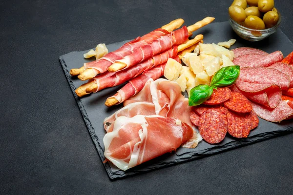 Prato de carne fumada a frio com costeletas de porco, presunto, salame e paus de pão — Fotografia de Stock