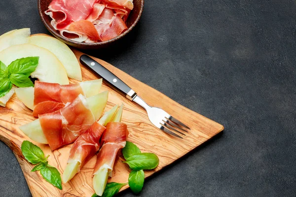 Olasz élelmiszer, dinnye és a prosciutto, a fa vágódeszka — Stock Fotó