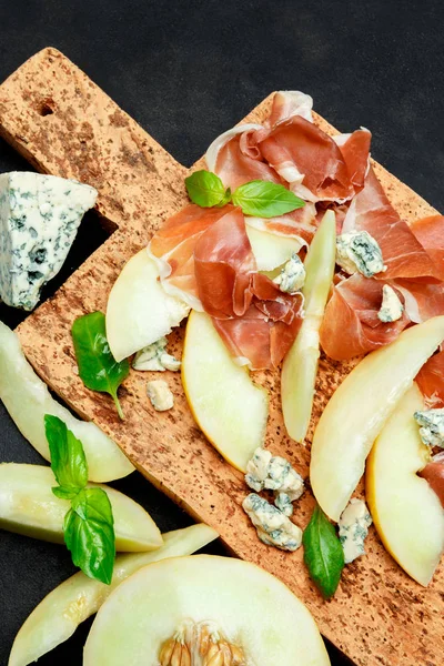 メロンと生ハム、コルクまな板の上のチーズのイタリア料理 — ストック写真