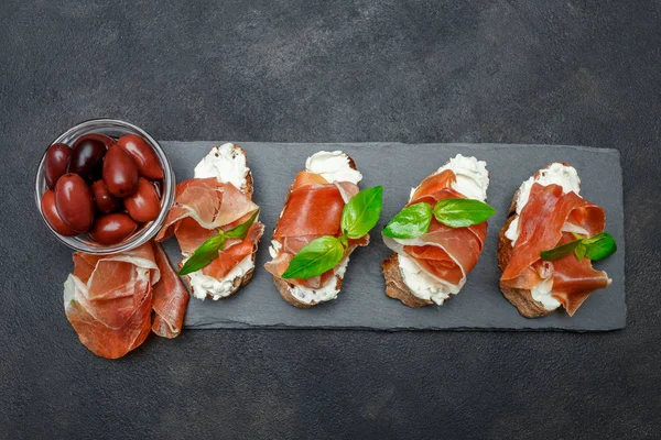 Alimentos italianos com azeitonas e prosciutto bruschettas sobre placa de pedra — Fotografia de Stock