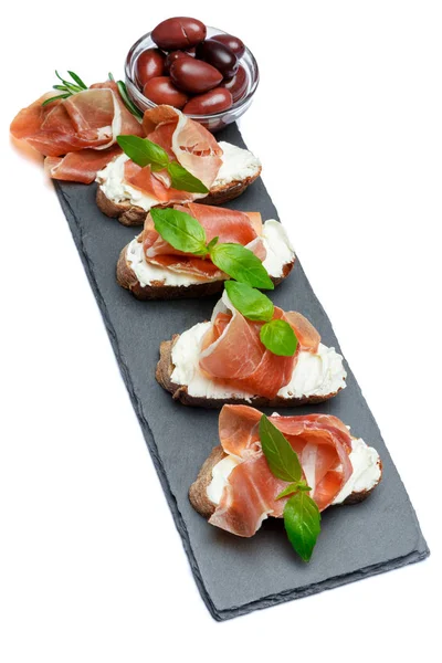 Alimentos italianos com azeitonas e prosciutto bruschettas sobre placa de pedra — Fotografia de Stock