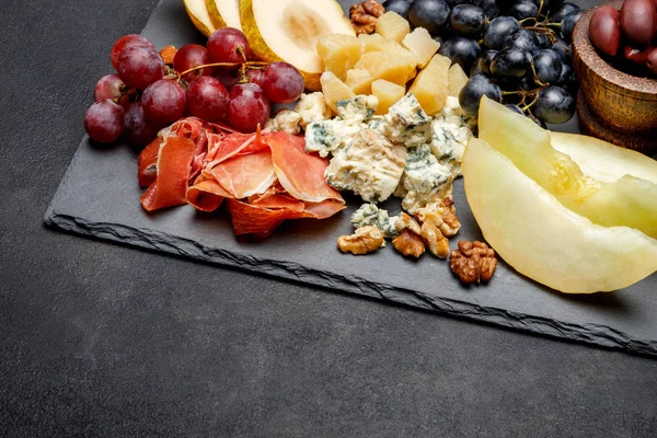 Placă de carne gustare antipasti șuncă Prosciutto, brânză albastră, pepene galben, struguri, măsline — Fotografie, imagine de stoc