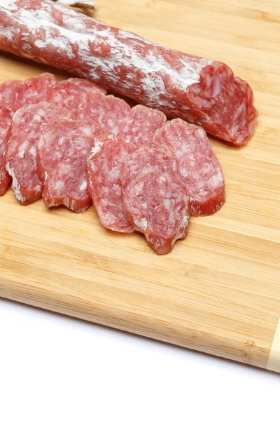 Salchicha de salami orgánica en rodajas secas en tabla de cortar de madera — Foto de Stock