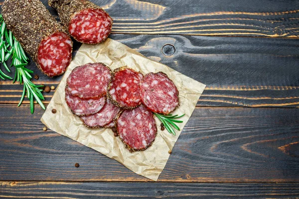 Dried organic salami sausage covered with pepper on wooden background — Stock Photo, Image