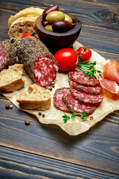 Salsiccia di salame biologico essiccato coperto con pepe su sfondo di legno — Foto Stock