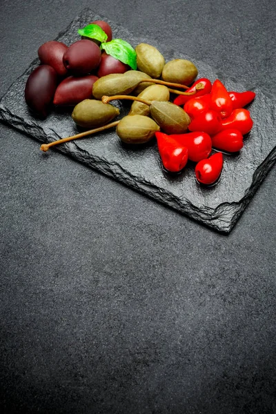 Gemischte Essiggurken auf Steinplatten. Oliven, Kapern und Paprika — Stockfoto