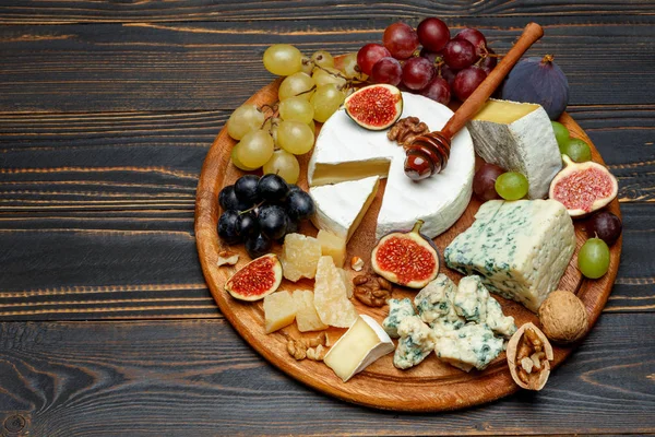 Queijo Brie em uma tábua de madeira com figos frescos e uvas — Fotografia de Stock