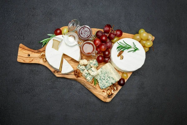 Diverse soorten kaas en jam op houten snijplank — Stockfoto