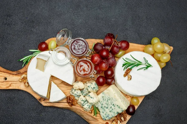 Diverse soorten kaas en jam op houten snijplank — Stockfoto