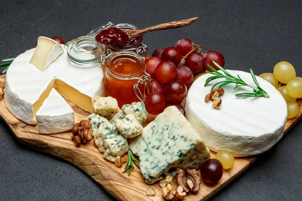 Vários tipos de queijo e geléia na placa de corte de madeira — Fotografia de Stock