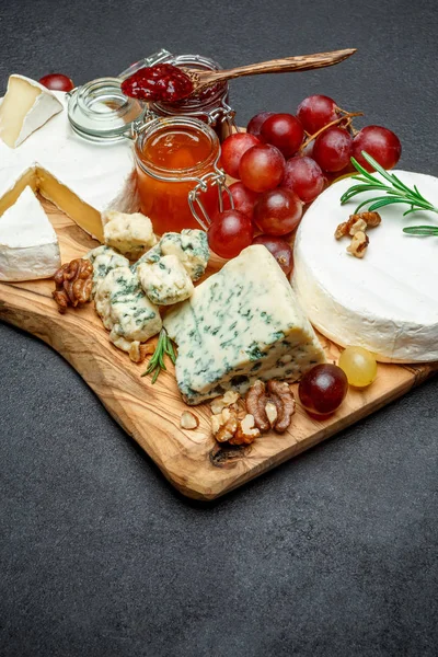 Vari tipi di formaggio e marmellata sul tagliere di legno — Foto Stock