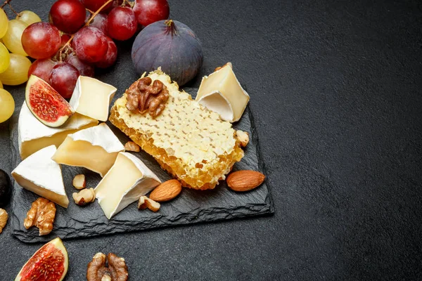 Камамбер с медом, инжиром, грецкими орехами на каменной доске — стоковое фото