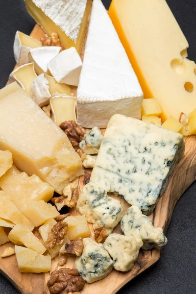 Различные сорта сыра на деревянной доске — стоковое фото