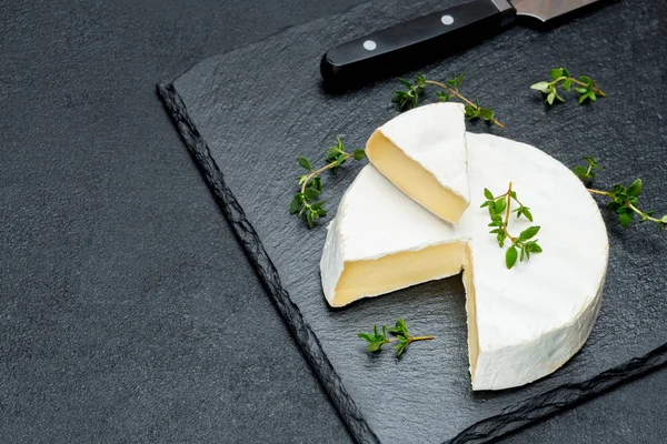 Camembert fromage et couper une tranche sur la plaque de service en pierre — Photo