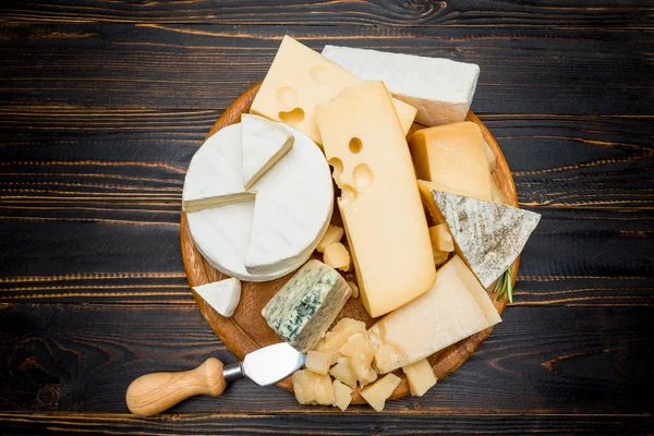 Various types of cheese - brie, camembert, roquefort and cheddar on wooden board — Stock Photo, Image