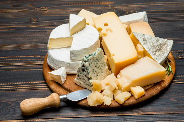 Various types of cheese - brie, camembert, roquefort and cheddar on wooden board — Stock Photo, Image