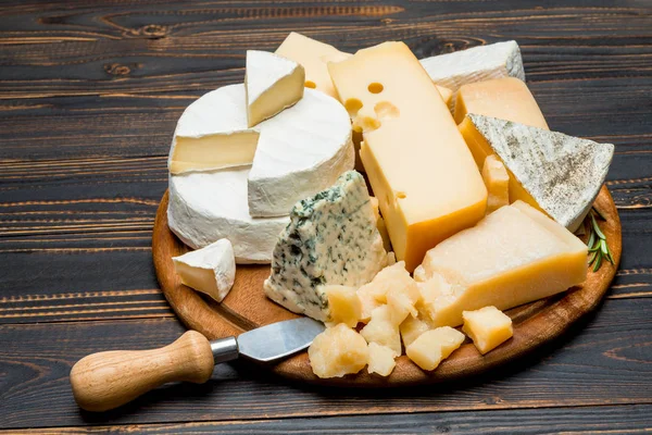 Vários tipos de queijo - brie, camembert, roquefort e cheddar em tábua de madeira — Fotografia de Stock