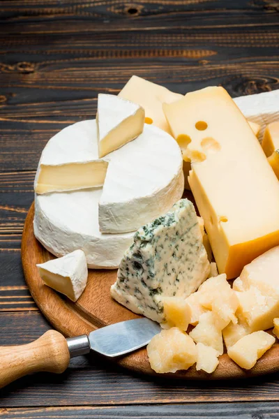 Différents types de fromage - brie, camembert, roquefort et cheddar sur du bois — Photo