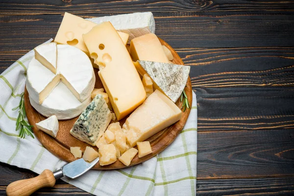 Diverse soorten kaas - brie, camembert, roquefort en cheddar op houten bord — Stockfoto