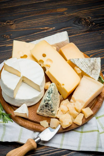 Various types of cheese - brie, camembert, roquefort and cheddar on wooden board — Stock Photo, Image